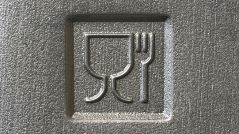 A piece of plastic with a fork and wine glass symbol indicating that the container is food grade