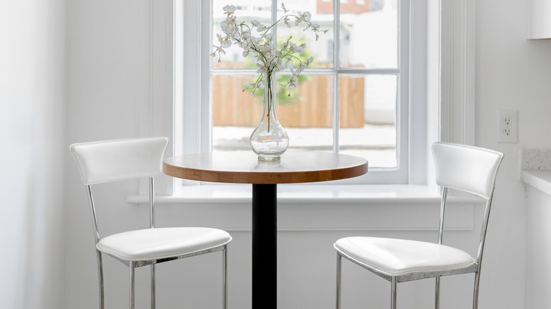 White breakfast nook with tall chairs around a round table by a window