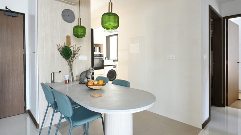 Breakfast table with blue chairs, green lights, and a cat sitting on the table