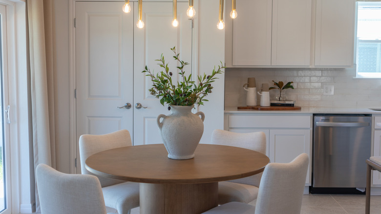 Elegant breakfast nook with four upholstered chairs around a round table with a vase