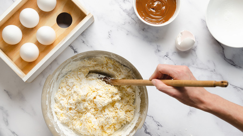 Closeup view of eggs on a marble surface with mixing bowl and baking ingredients