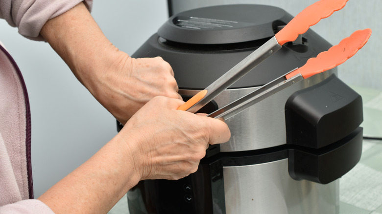 Woman opening the lid of a large pressure cooker