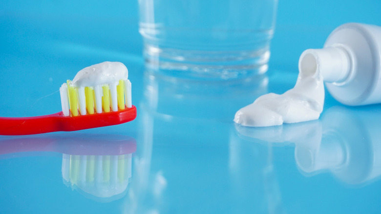 A red tooth brush with tooth paste on it on a blue countertop
