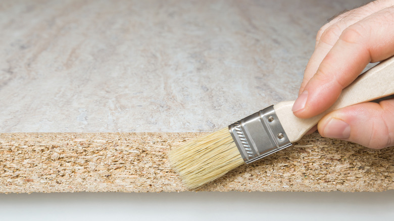 A hand painting a coating on a laminate counter