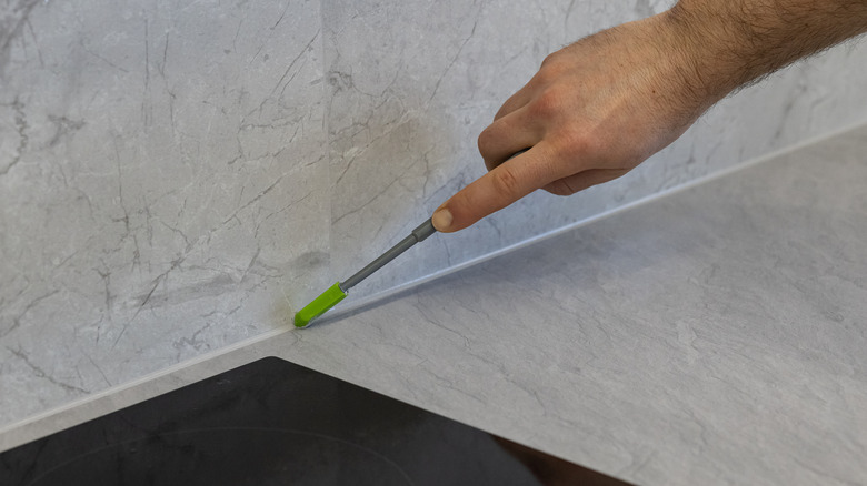 A man applying sealant to a kitchen countertop edge