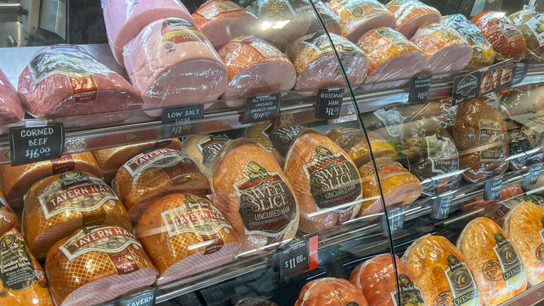 Several unsliced deli meats in a deli case