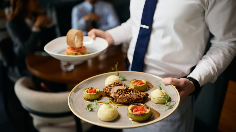 waiter carrying elegant plates of food