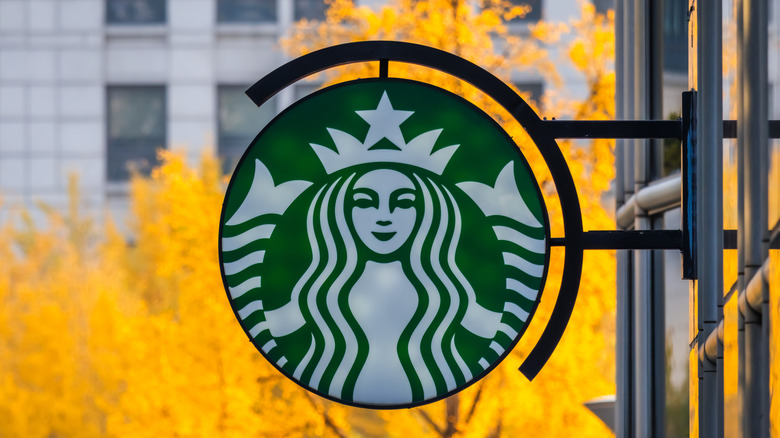 Starbucks logo with a yellow-leaved tree in the background