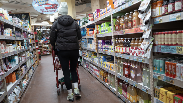 Person in a hat pushing a cart through a Trader Joe's store