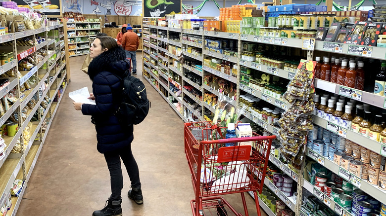 Woman in the aisle shopping at Trader Joe's with shopping list