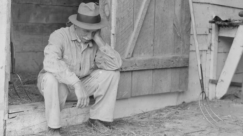 discouraged American farmer with pitchfork 1930s