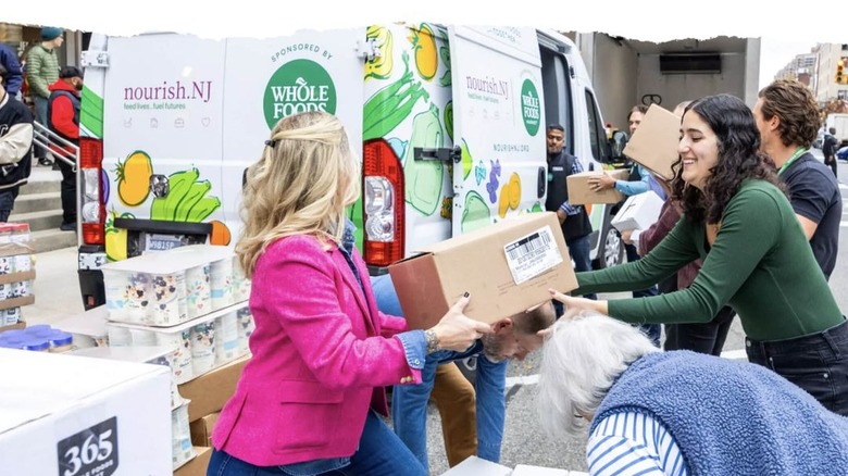 Two women handing a cardboard box between them at a Whole Foods food donation event.