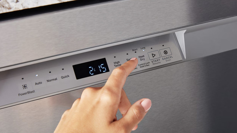 A dishwasher control panel with a pointing hand