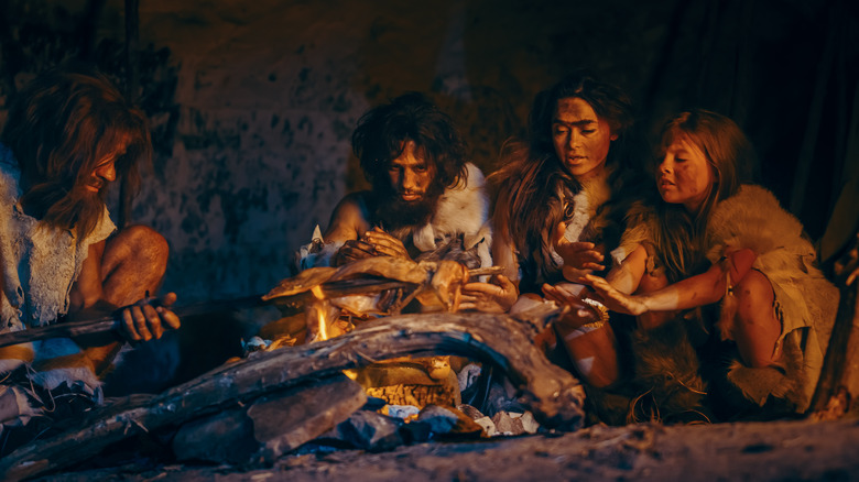 ancient ancestors cooking while sitting around a fire