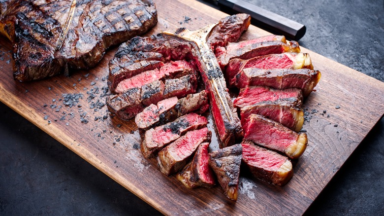 seared and sliced t-bone steak on cutting board