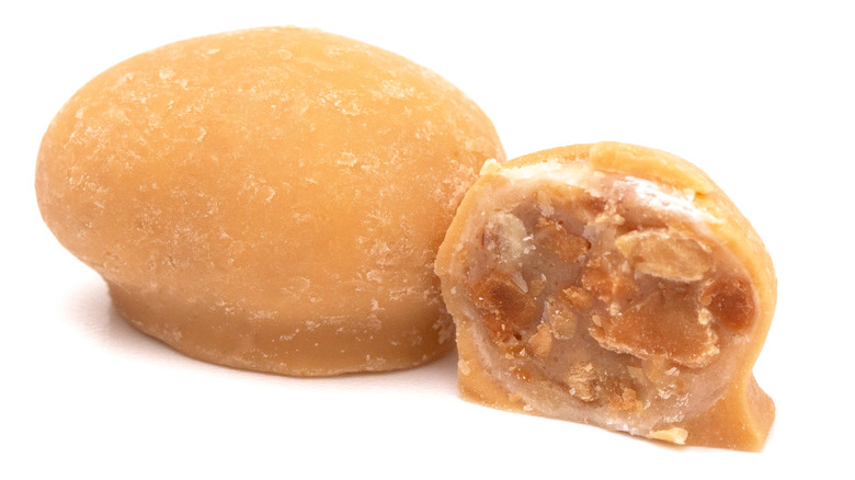 A whole Maple Nut Goodie candy alongside one that has been cut in half to show the center