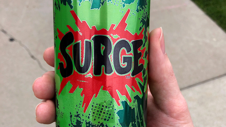 SURGE soda can in hand