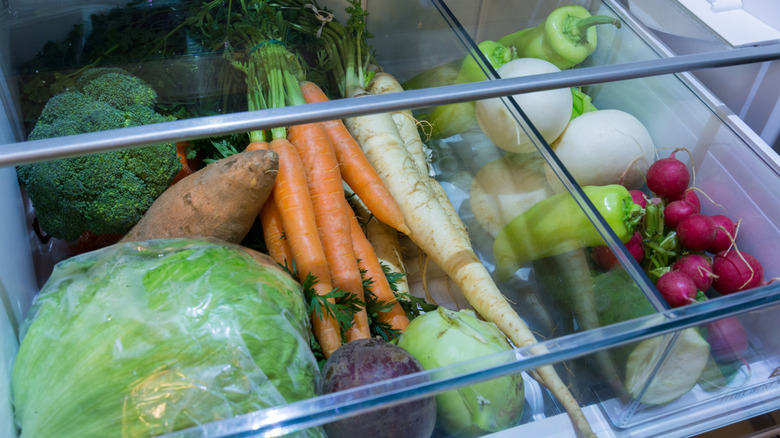 Open fridge drawer full of fresh veggies, including sweet potatoes