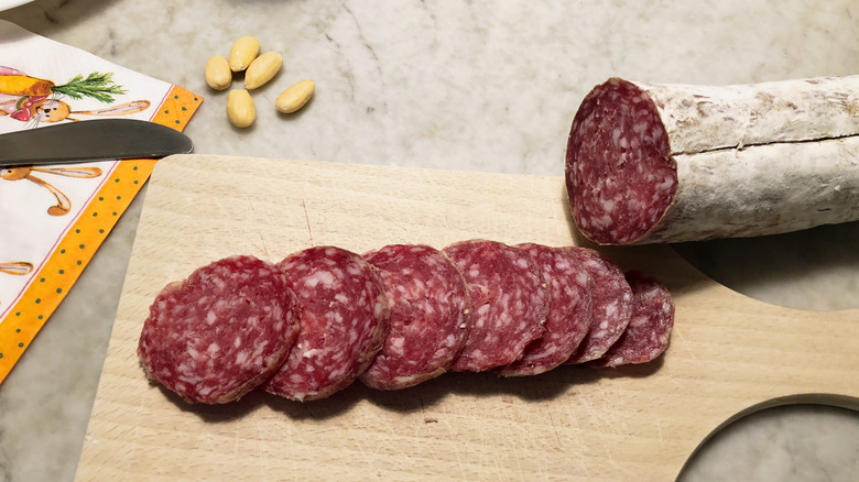 roll of pepperoni cut on wood board