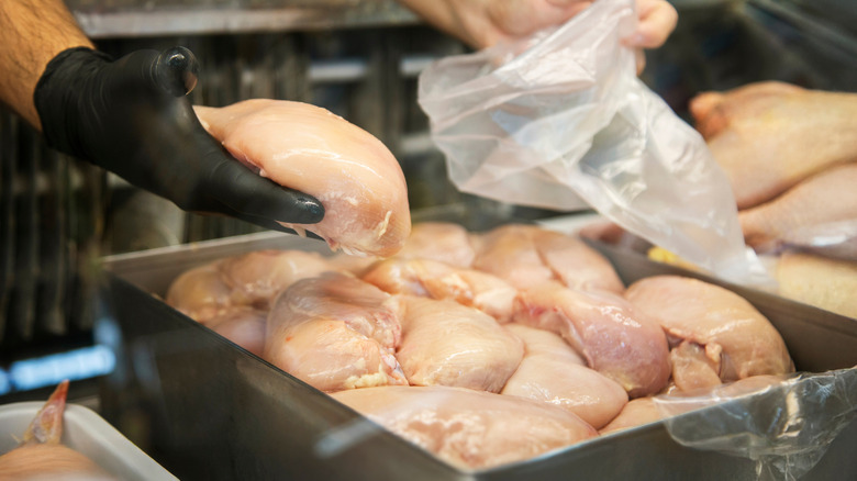Person holding raw chicken cuts.