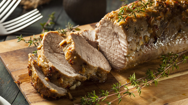 Roasted pork tenderloin with herbs on cutting board