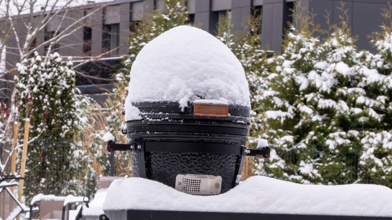 A Kamado grill outside covered in snow in backyard