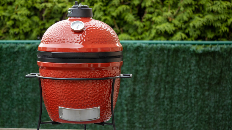 red Kamado style grill on wooden table