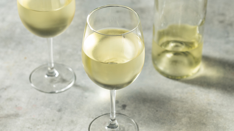 A cold glass of sauvignon blanc with another glass and half empty bottle seen in the background
