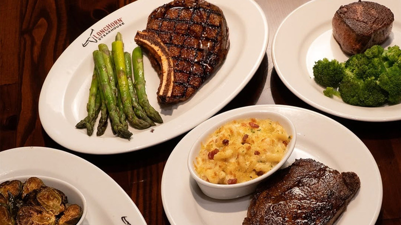 Various plated LongHorn Steakhousesteaks and sides on a table