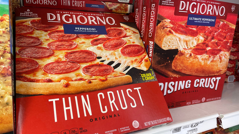 DiGiorno pepperoni pizza boxes, one thin crust and one rising crust, sitting in a grocery store freezer.