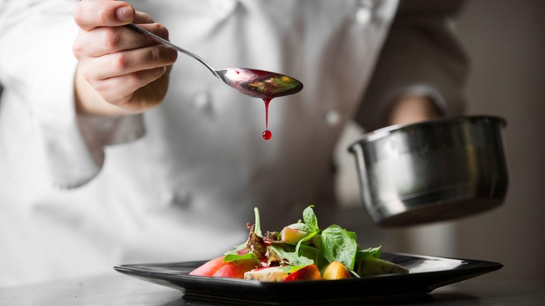 Close-up of a cook plating a dish
