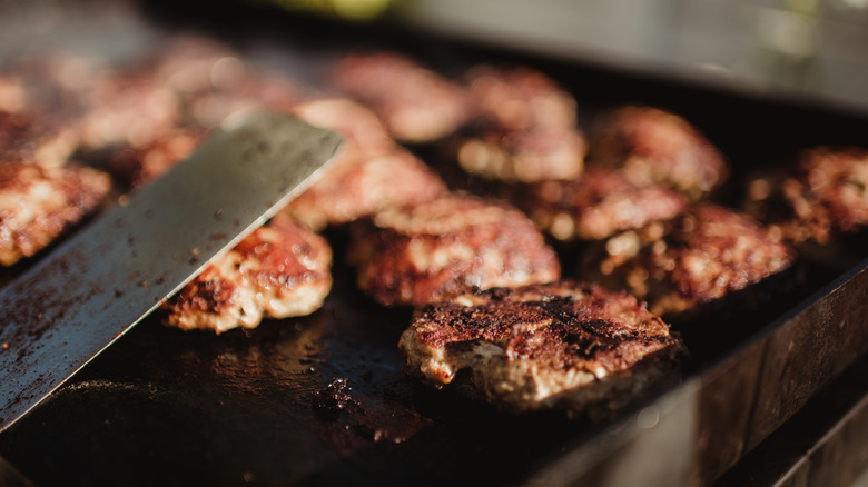 Closeup of cooking burgers on a flat-top grill or griddle surface