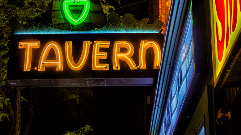 An illuminated neon sign for a tavern on a dark evening