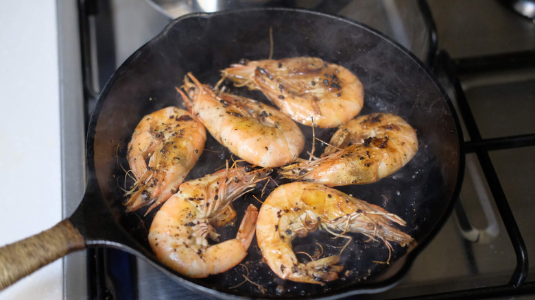 Tiger prawns cooking in a cast iron skillet on the stove