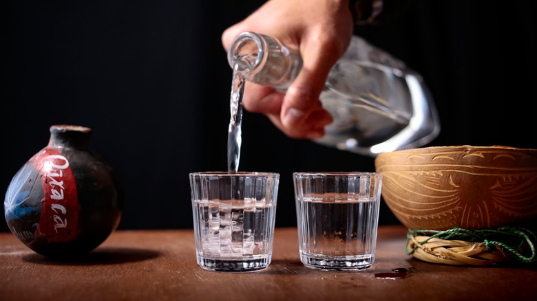 Pouring two glasses of mezcal