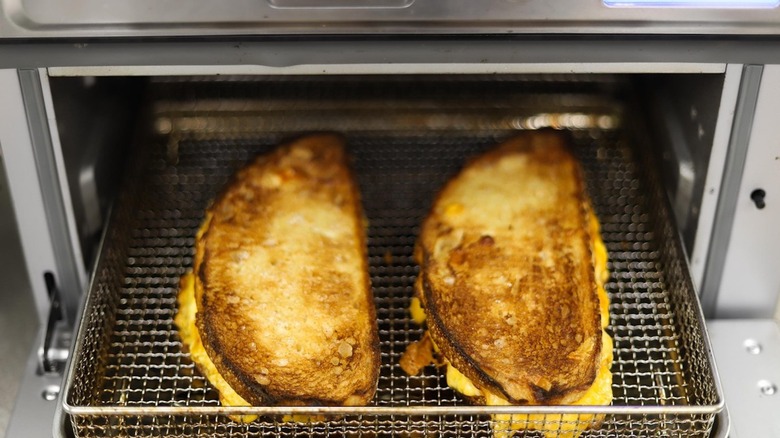 Grilled cheeses sit in air fryer basket 
