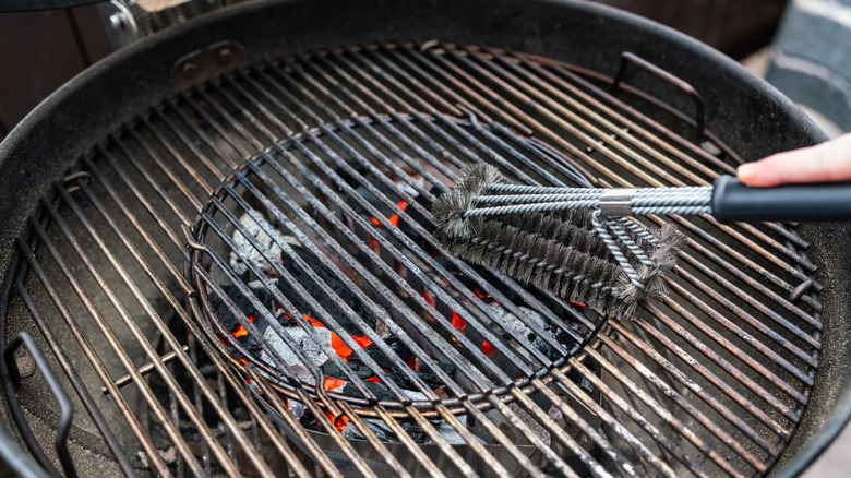 person cleaning the grates of their grill