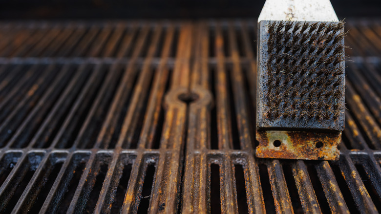 cleaning a rusty grill with a grill brush