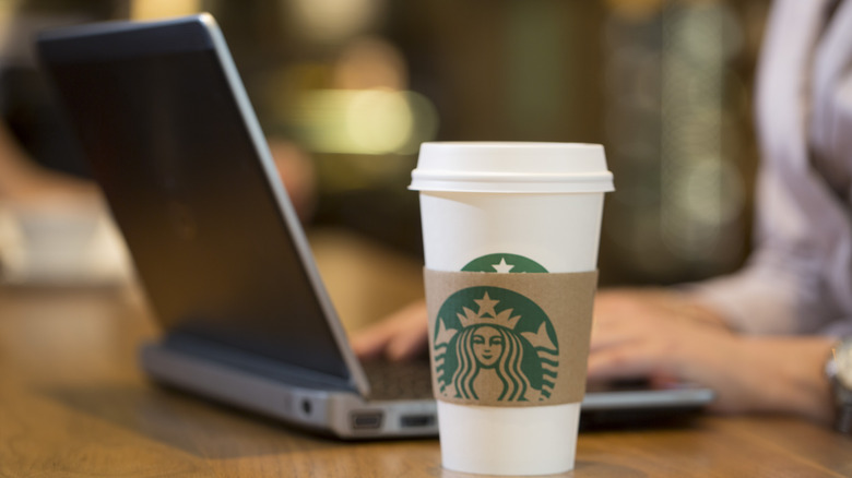 person on laptop with starbucks cup