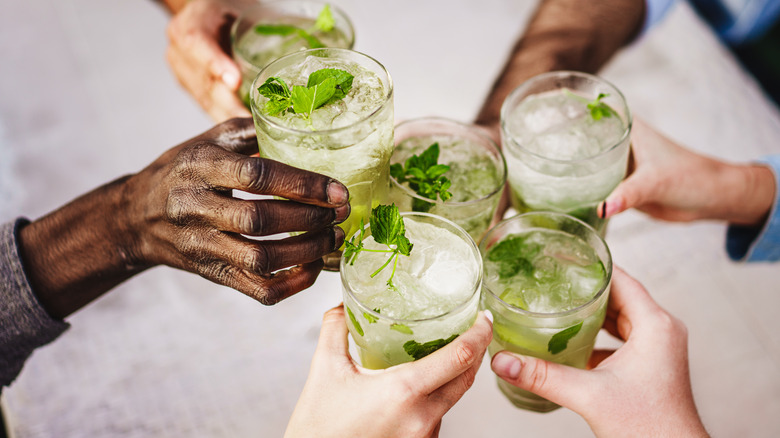 Friends clinking mojito glasses with fresh mint