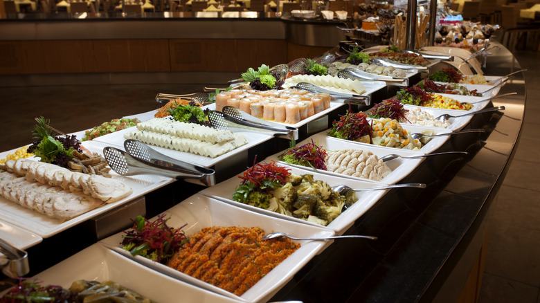 A buffet at a hotel with sushi, brocolli, sweet potatoes, cheese