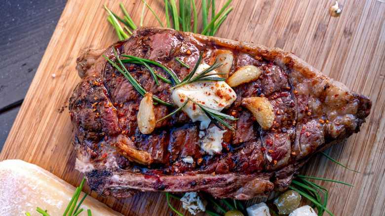 seared steak resting with a topping of herbs, spices, and garlic