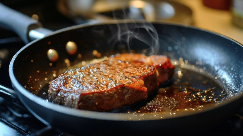 a steak searing in a frying pan