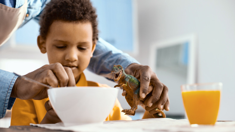 kid with dinosaur eating cereal