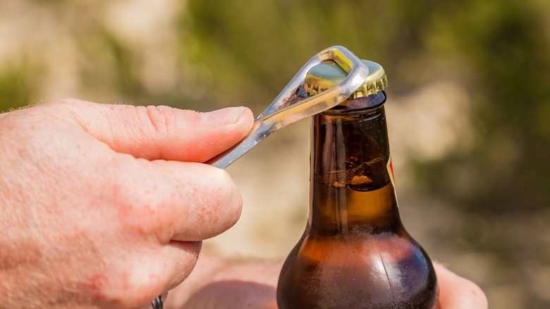 opening a beer with a bottle opener