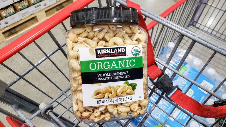 A container of Kirkland Signature organic cashews in a Costco cart