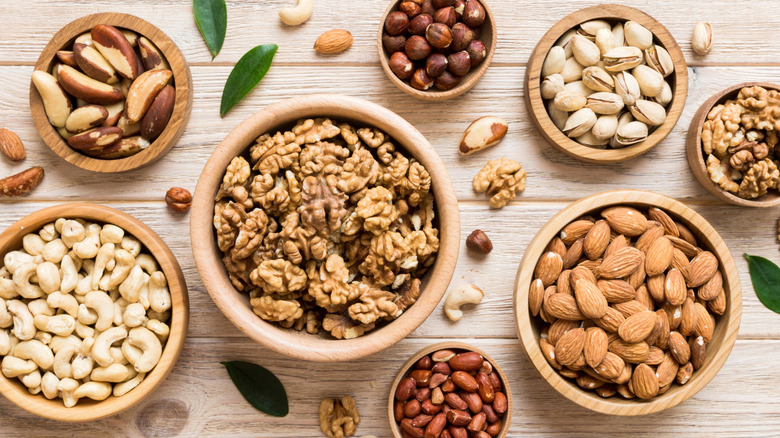 Various nuts all arranged in different wooden bowls