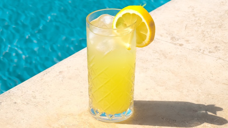 A glass of lemonade beside a swimming pool