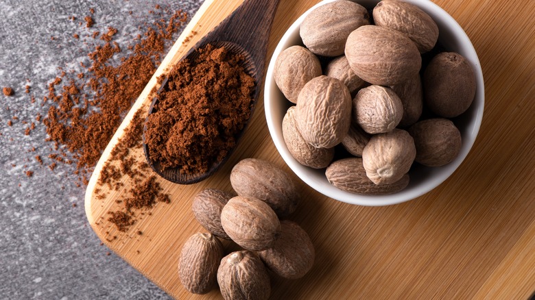 whole and ground nutmeg on a wooden tray