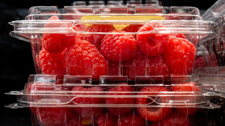 Boxes of raspberries on a shelf in a supermarket waiting to be sold